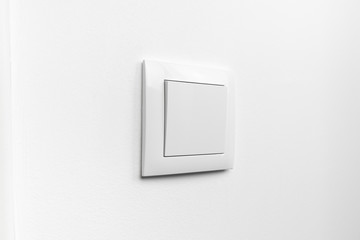 Modern white electrical light switch on a white painted wall