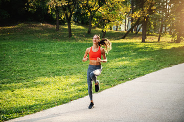 Fototapeta premium Full length of young handsome slim sportswoman with healthy habits running in nature in the morning.