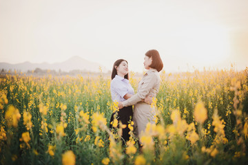 Young Asian Teacher with students  walking through Crotalaria flower field and enjoy at sunset
