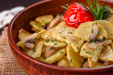 Rustic potato wedges with cheese, herbs and tomato sauce on black background