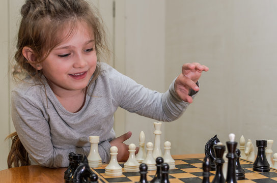 Little charming girl child playing chess