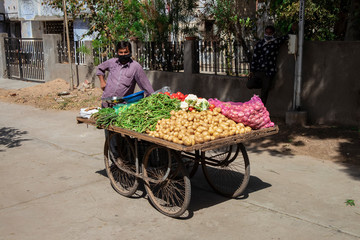 NARODA GUJARAT/INDIA - MARCH 30, 2020: Indian man carries a cart with vegetables on the road....