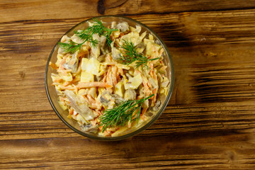 Tasty salad with chicken breast, roasted mushrooms, carrots, grated cheese, eggs and mayonnaise on wooden table. Top view