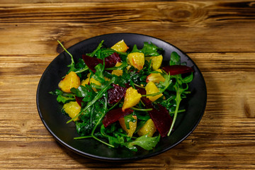 Tasty salad of fresh arugula, beetroot and oranges on wooden table. Healthy food or vegetarian concept