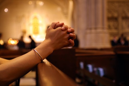 Closeup of woman's hands praying on church bench, coronavirus, copy space