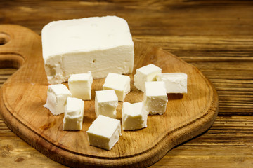 Feta cheese on cutting board on a wooden table