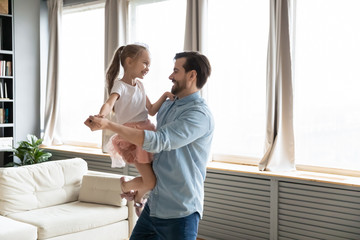 Loving dad holds on hands small daughter she wears crown imagines herself like princess, people...