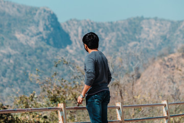 Fototapeta na wymiar Indian male tourist standing in front of the mountains at Polo Forest in Gujarat, India