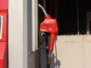 The Fuel pump. Detail of a red hand holding a fuel pump at a station.