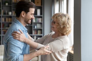 Elderly mother admires matured adult son looking at him smiles enjoy long awaited meeting after...