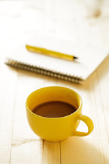 cup of hot chocolate on wooden background with notebook.  Work from home concept.