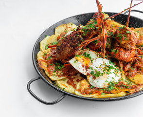 Formentera Lobster with fried potatoes, eggs and parsley in a traditional paella pan. Caldereta de bogavante de Formentera
