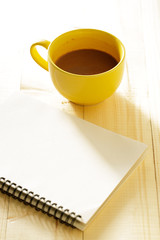 cup of hot chocolate on wooden background with notebook.  Work from home concept.