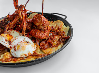 Formentera Lobster with fried potatoes, eggs and parsley in a traditional paella pan. Caldereta de bogavante de Formentera