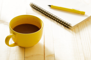 cup of hot chocolate on wooden background with notebook.  Work from home concept.