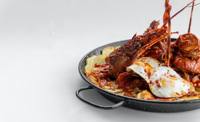 Formentera Lobster with fried potatoes, eggs and parsley in a traditional paella pan. Caldereta de bogavante de Formentera