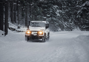 vintage sport utility vehicle driving during snow storm in forest
