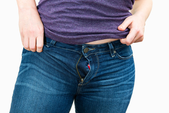 Woman struggling to put on jeans that are too tight / diet and weight gain concept