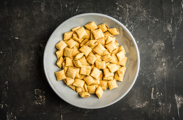 Wholegrain pillow cereals in bowl on the rustic background. Selective focus. Shallow depth of field.