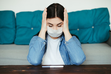 Pregnancy and virus diseases epidemic. Coronavirus spreading prevention. Health care. Upset and disturbed woman in medical face mask with pregnancy test