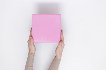 Pink parcel cardboard box in a delivery woman hands on a white background. Delivery service concept.