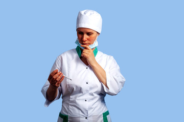 female doctor in a white coat in a medical mask with a thermometer in hand
