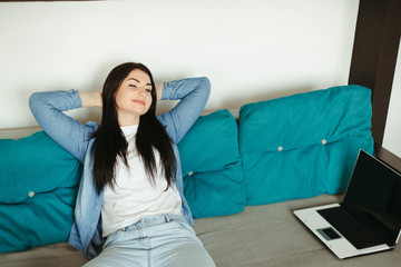 Young woman relaxing on a couch in living room. Home, coziness, dreaming and harmony