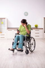 Young male invalid in wheel-chair suffering at home