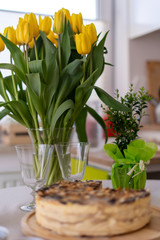 Festive Easter table setting with a basket for traditional meals, eggs in nest, fresh yellow tulips, marshmallows, selective focus banner