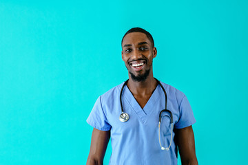 Portrait of a happy male doctor or nurse wearing blue scrubs uniform and smiling, isolated on blue studio background