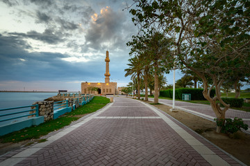 Beautiful view of Hanan Ali Kanoo Mosque in Al Ghous park and Manama city at the background with striking clouds during sunset.