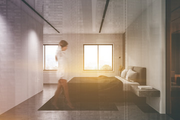 Woman walking in white master bedroom
