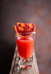 Strong red cocktail in shots on the rustic background. Selective focus. Shallow depth of field.