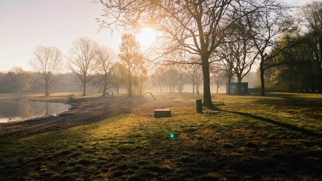 Morning sun shining through trees surrounding an empty playground near Unisee in Bremen
