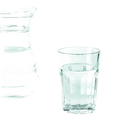 Pure clear water in a glass glass and glass jug stands on a white background