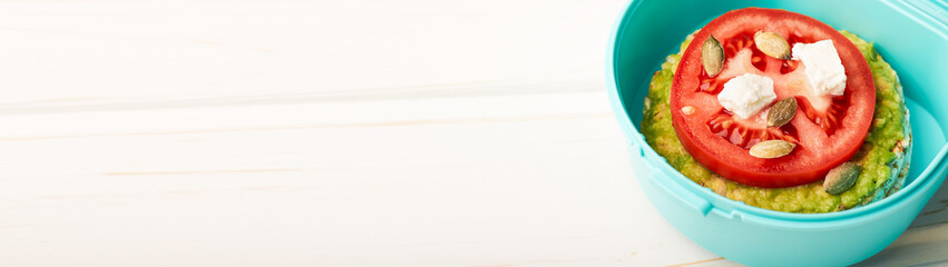 Lunch box with rice cake with avocado tomato with feta rice and pumpkin seeds web banner with copy space