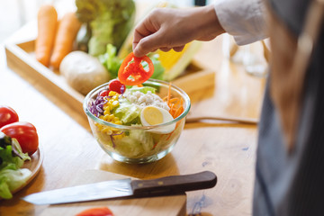 Closeup image of a female chef cooking a fresh mixed vegetables salad in kitchen