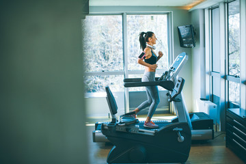 Fototapeta na wymiar Young woman running on treadmill during sports training in a gym