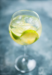 Rum based cocktail with lime in wine glass (variation of cuba libre) on the rustic background. Selective focus. Shallow depth of field.
