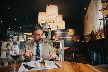 Handsome mature man drinking red wine during lunch