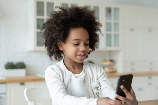Cute little African American girl study online talk on video call on cellphone with teacher, smiling small biracial child have web class or lesson on smartphone at home, homeschooling concept