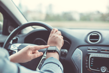 Close up of woman using smart watch during driving her car, transport concept