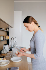 Obraz na płótnie Canvas Beautiful woman break chicken eggs in a plate in the kitchen. Cooking dough.