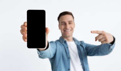 Focus on blank screen. Guy points finger at smartphone