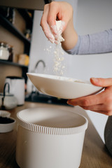 Fototapeta na wymiar Authentic woman hands sprinkling flour in a bowl holding a whole plate in the hand while cooking in the kitchen