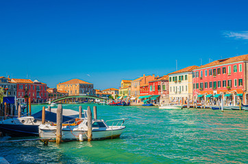 Murano islands with bridge across water canal, boats and motor boats, colorful traditional buildings, Venetian Lagoon, Province of Venice, Veneto Region, Northern Italy. Murano postcard cityscape.