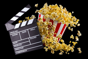 Flying popcorn and film clapper board isolated on black background