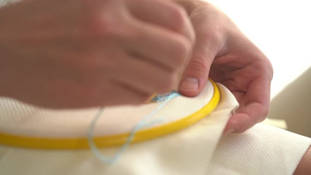 side close up of cross-stitching, needlework 4k. female hands embroider a picture