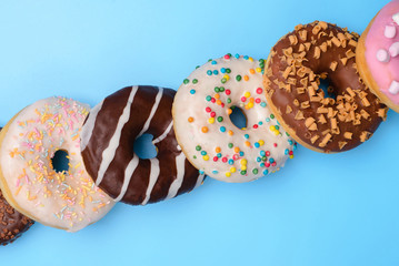 Top above overhead close up view photo of different yummy donuts lying in a row isolated over...