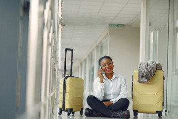 Fototapeta na wymiar Black woman at the airport. Girl with suitcase. Lady in a white shirt.